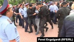 Қазақстанда кезектен тыс президент сайлауы күні үкіметке наразылық шеруі өтіп жатқан жерде хабар әзірлеп жүрген Азаттық тілшісі Петр Троценконы (ортада) полицияның ұстаған сәті. Алматы, 9 маусым 2019 жыл.