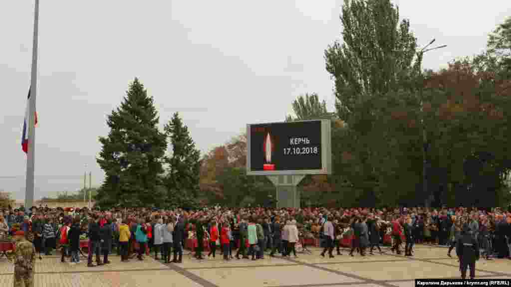 На площі Леніна стоять у ряд 17 закритих трун із тілами жертв трагедії. Поряд із кожним із них – фотографії й таблички з іменами загиблих. Грає жалобна музика. На великому екрані зображена свічка й напис «Керчь 17.10.2018»