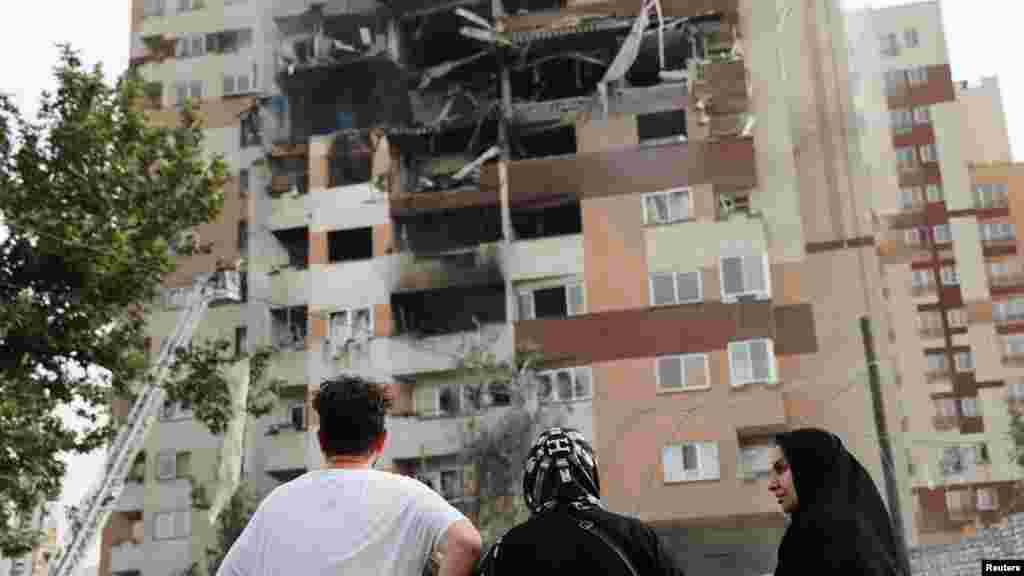 Locuitori din capitala Iranului, Teheran, privesc o clădire afectată de loviturile israeliene din 13 iunie.