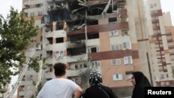 Iran - People look at a damaged building in the aftermath of Israeli strikes, in Tehran, June 13, 2025. 