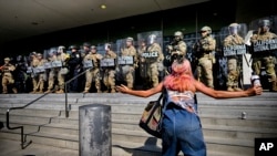 Un protestatar în fața unei linii a Gărzii Naționale din California care protejează o clădire federală în centrul orașului Los Angeles. Luni, 9 iunie 2025.