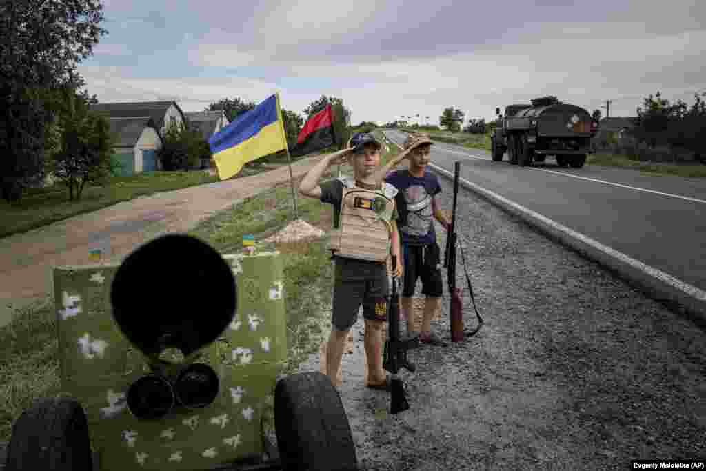 11-річні Максим та Андрій віддають честь українським військовим зі свого «блокпосту» на трасі в Харківській області, 20 липня 2022 року