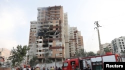 Pompierii lucrează la locul unei clădiri avariate în urma atacurilor israeliene, la Teheran, Iran, 13 iunie 2025.