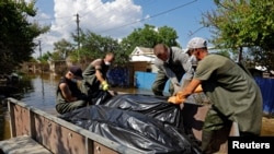 Российские спасатели и волонтеры собирают тела погибших во время наводнения в Голой Пристани, 16 июня 2023 года