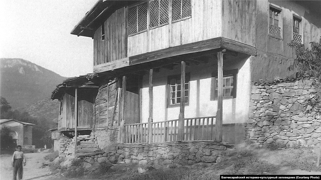 Сільський будинок. Південно-Західний Крим, 1920-ті. Стандартний інтер&#39;єр головної кімнати передбачав відкритий камін з димарем і підвішений до нього на ланцюгу казан. Уздовж стін стояли низькі диванчики з матрацами і подушками, поруч &ndash; столики. Стіни прикрашали численними рушниками, а підлоги &ndash; килимами