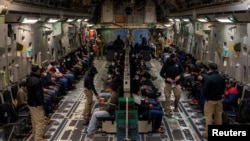 Migranții reținuți așteaptă decolarea într-un zbor C-17 Globemaster III al Forțelor Aeriene ale SUA pe Aeroportul Internațional Tucson din Tucson, Arizona, 23 ianuarie 2025.