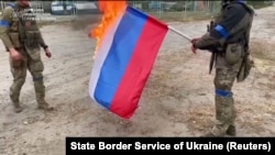 Українські військовослужбовці спалюють російський прапор у звільненому від російської армії місті Вовчанську (Харківська область), розташованому на кордоні з Росією. Кадр з відео, яке вийшло 13 вересня 2022 року